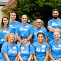 Alumni pose in front of the Alumni House